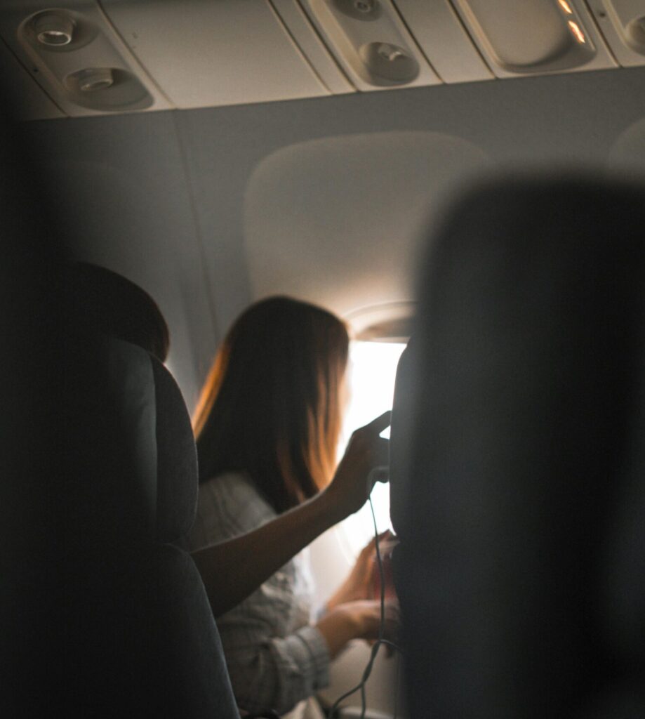 A woman looks out the airplane window, capturing the serene atmosphere of air travel.