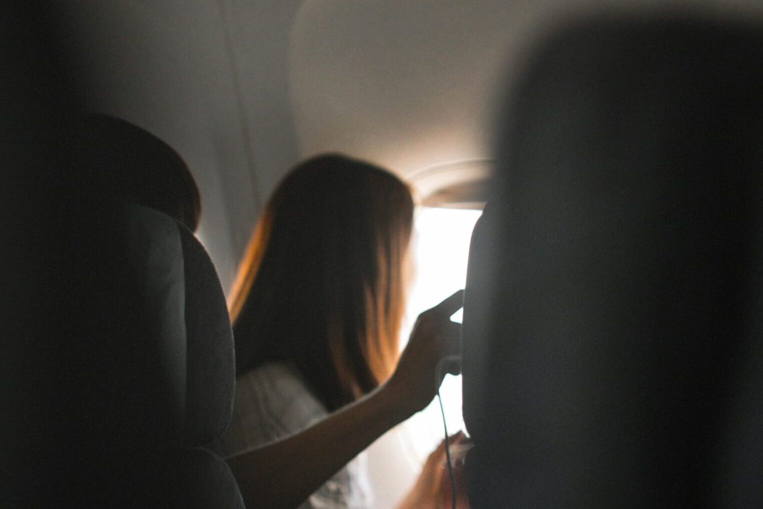 A woman looks out the airplane window, capturing the serene atmosphere of air travel.